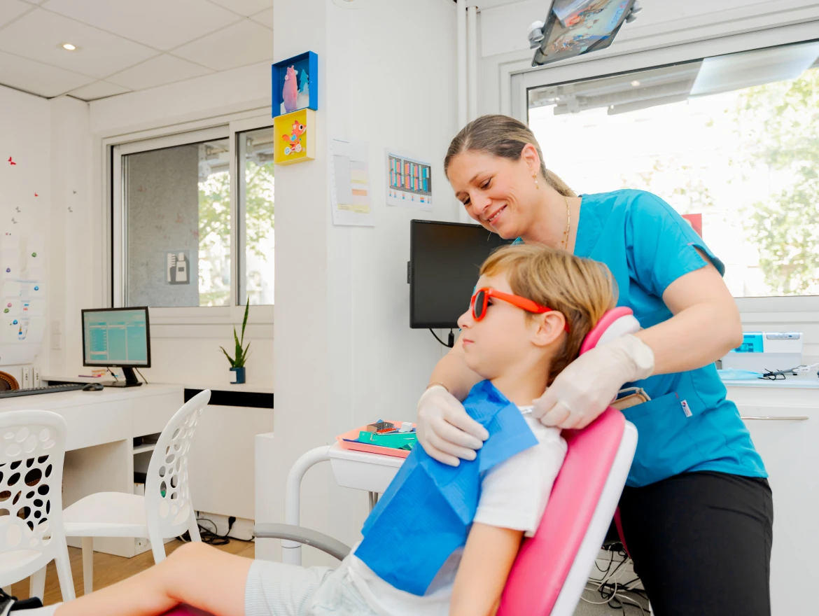 Praticienne soignant un enfant au fauteuil dentaire